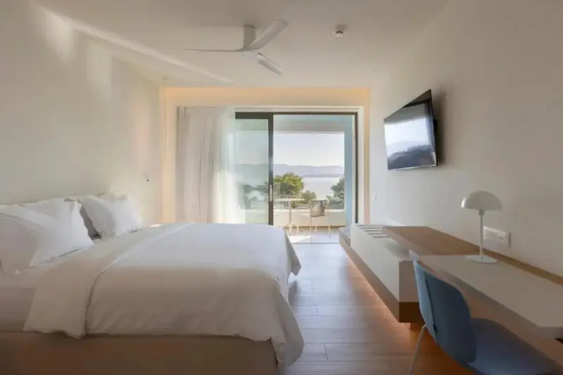 Chambre lumineuse avec un grand lit et une vue sur la mer.