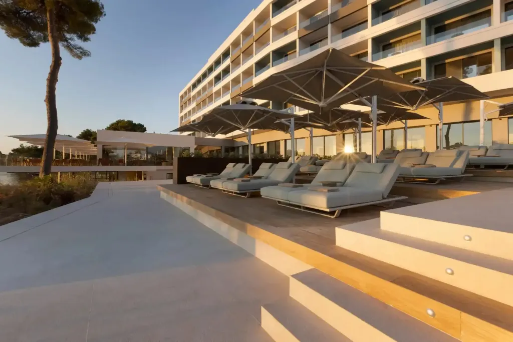 Terrasse avec transats et parasols devant un bâtiment moderne.