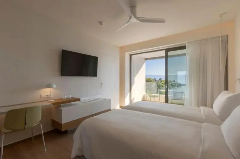 Une chambre lumineuse avec un lit double et un accès à un balcon.
