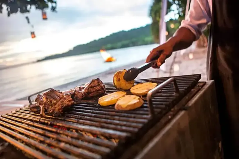 Préparation de grillades en extérieur face à la mer.