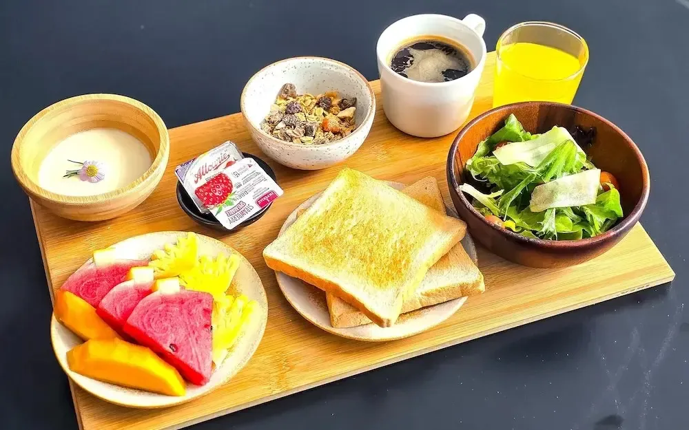 Un plateau de petit-déjeuner avec des fruits, des céréales, du yaourt et des boissons.