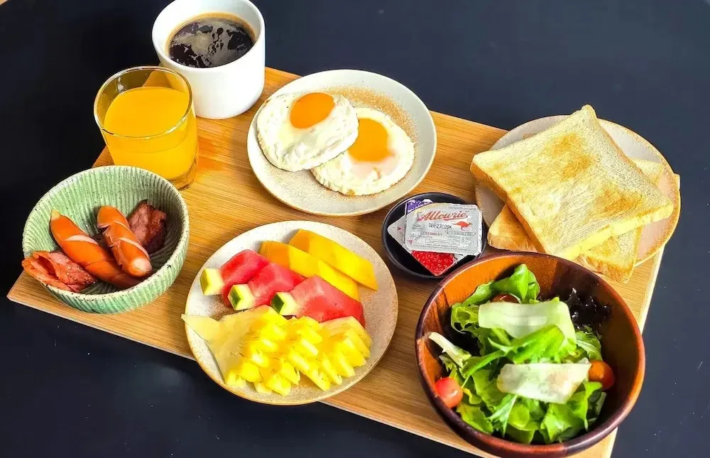 Un plateau de petit-déjeuner avec des œufs, des fruits, du pain grillé et des boissons.