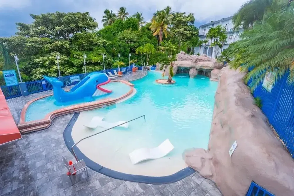 Une piscine avec des chaises longues et une structure en forme de dauphin.