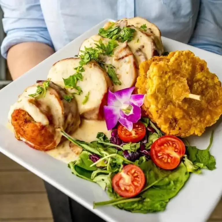 Assiette de viande blanche nappée de sauce, accompagnée de légumes et d'une fleur.