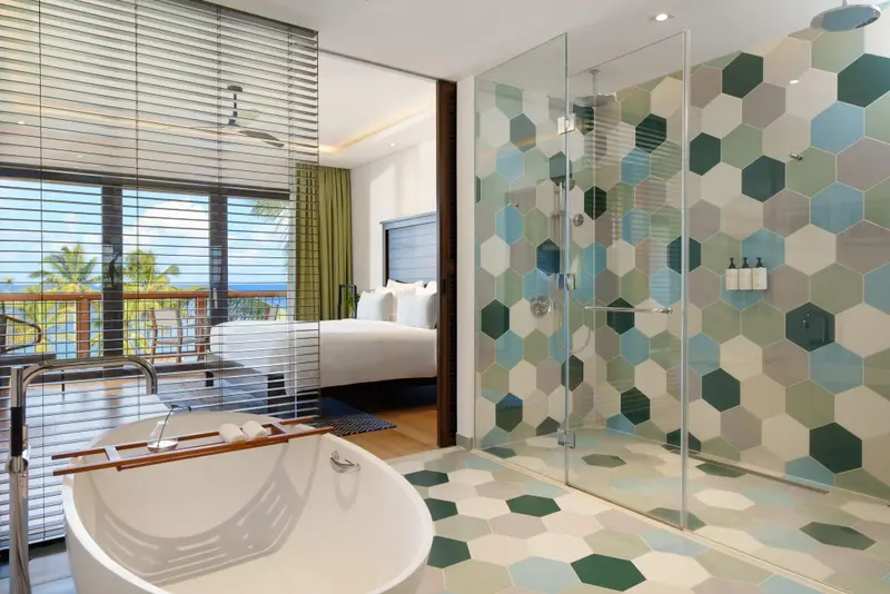 Une salle de bain moderne avec baignoire et douche à l'italienne donnant sur une vue sur la mer.