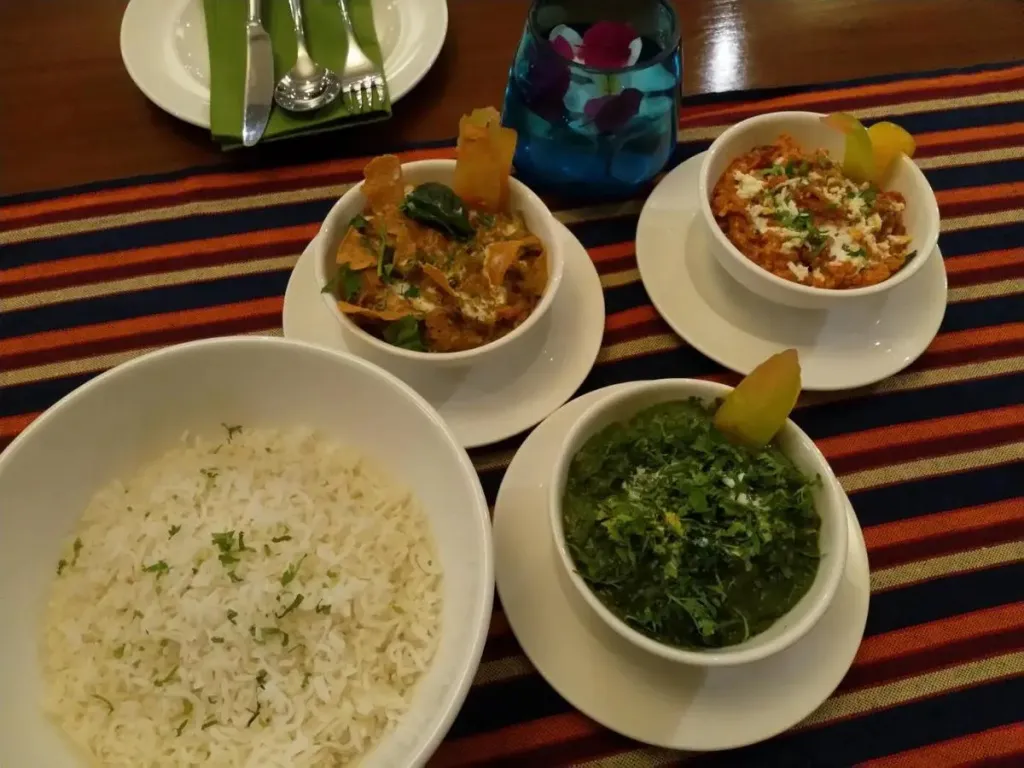 Assiette de riz, de curry et de légumes verts servis dans des bols blancs.