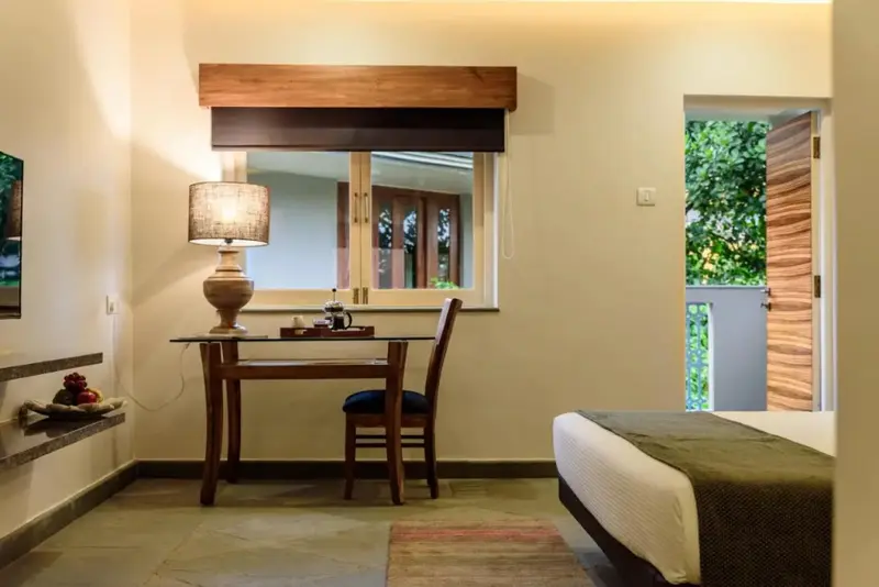 Une chambre lumineuse avec un bureau et un accès à un balcon.