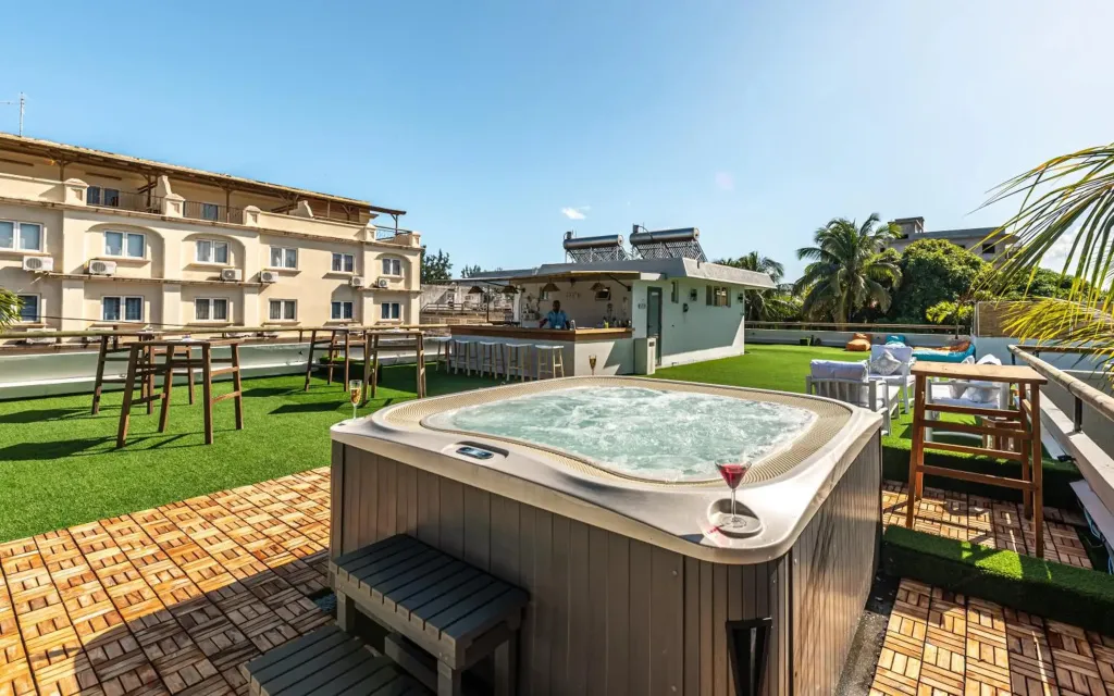 Un jacuzzi sur une terrasse avec des transats et un bar en fond.