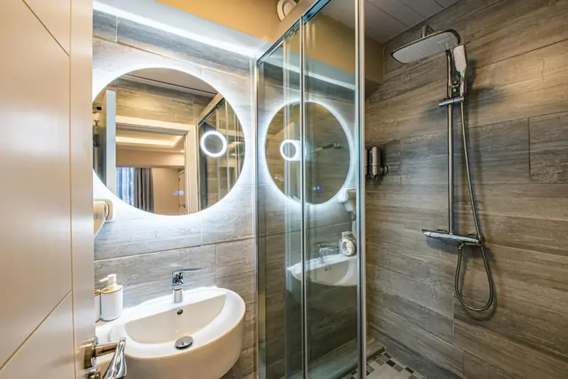Une salle de bain moderne avec douche à l'italienne et miroirs lumineux.