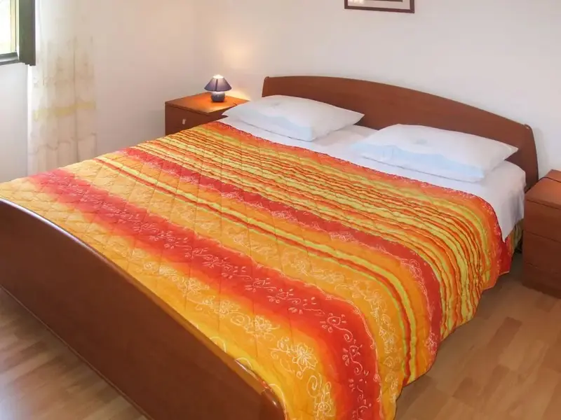 Une chambre avec un grand lit recouvert d'une courtepointe colorée.