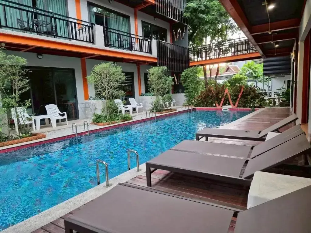 Transats alignés au bord d'une piscine rectangulaire dans une cour intérieure.