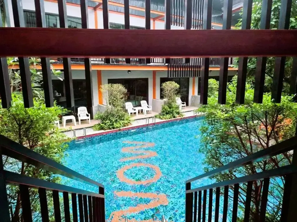 Une piscine bleue avec des transats blancs et des palmiers environnants.