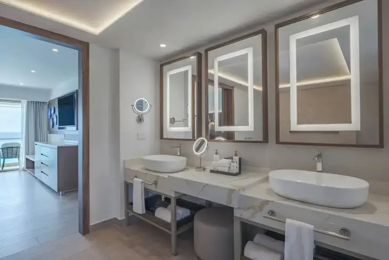 Une salle de bain lumineuse avec deux vasques et de grands miroirs.