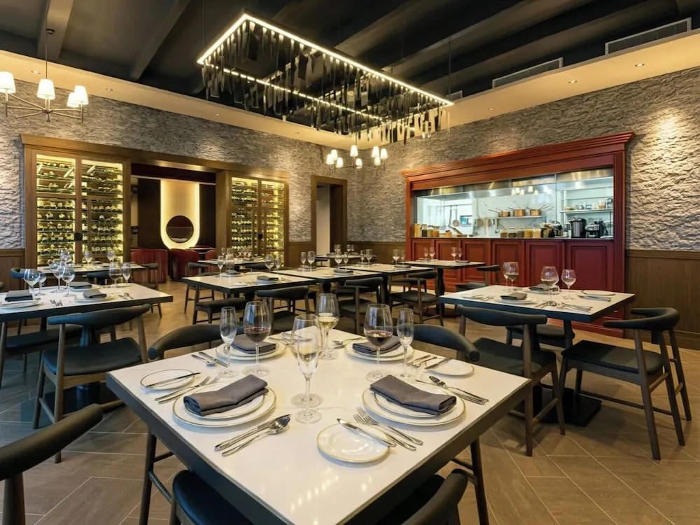 Une salle de restaurant élégante avec des tables dressées et un comptoir de cuisine ouvert.