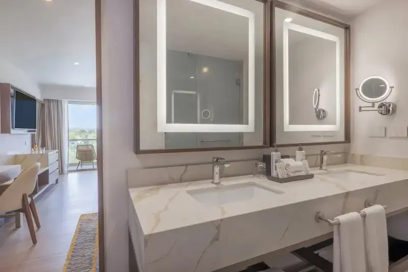 Une salle de bain lumineuse avec deux vasques et de grands miroirs.