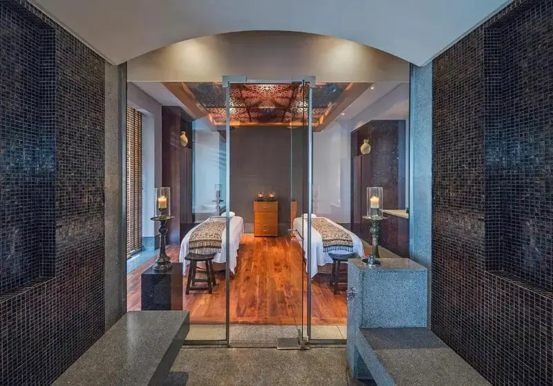 Deux tables de massage sont disposées dans une pièce lumineuse et décorée de mosaïques.