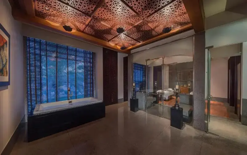 Une grande salle de bain lumineuse avec une baignoire et un accès à une chambre à coucher.