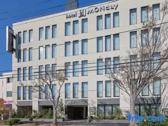 Facade d'un immeuble moderne avec des fenêtres rectangulaires et un panneau indiquant le nom de l'hôtel.