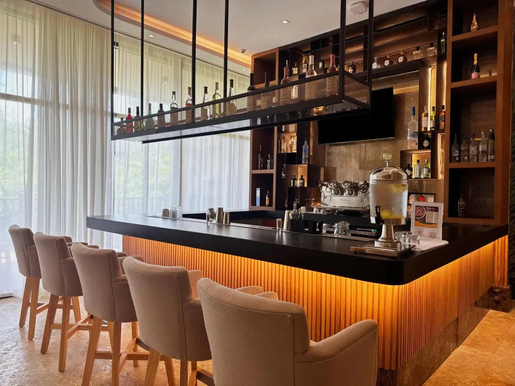 Un comptoir de bar moderne avec des tabourets et des bouteilles exposées.