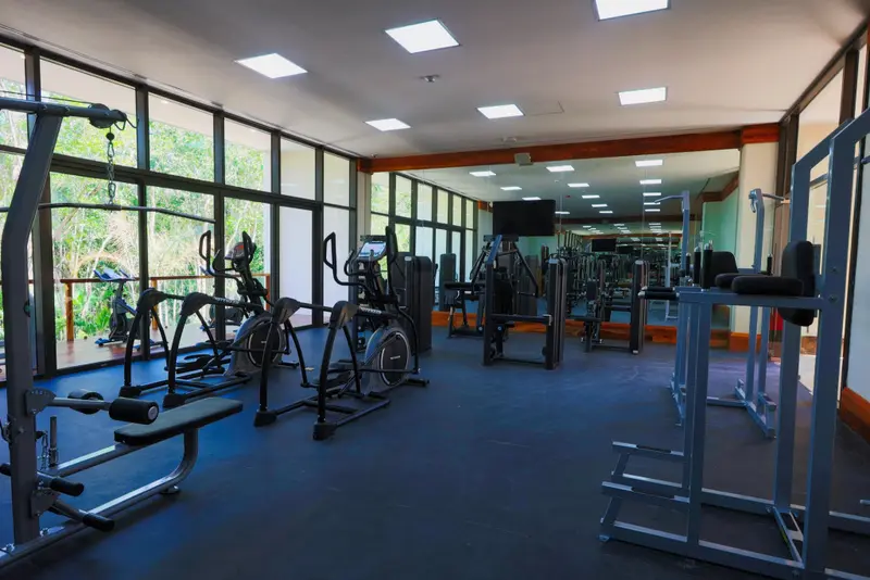 Une salle de sport lumineuse avec des équipements de musculation et des baies vitrées.