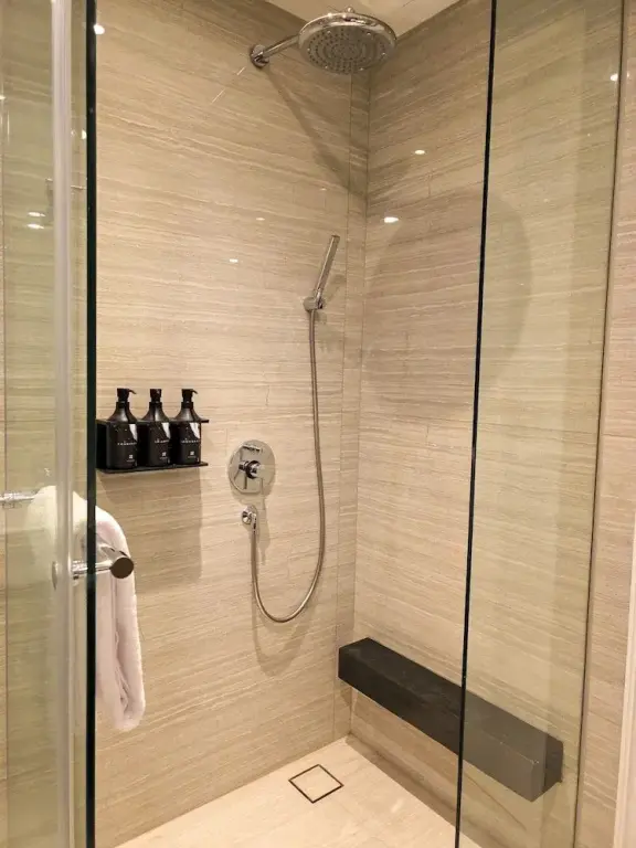 Une douche à l'italienne avec parois vitrées et pommeau de douche.