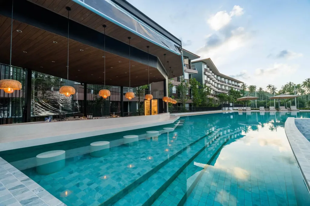 Une piscine avec un bar intégré et des transats au bord.