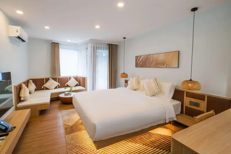 Une chambre lumineuse avec un grand lit et un coin salon.