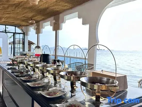 Un buffet propose une variété de plats dans un espace lumineux avec vue sur la mer.