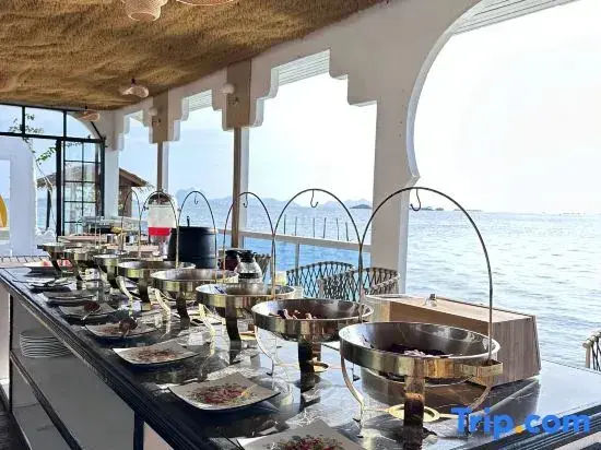 Un buffet propose une variété de plats dans un espace lumineux avec vue sur la mer.