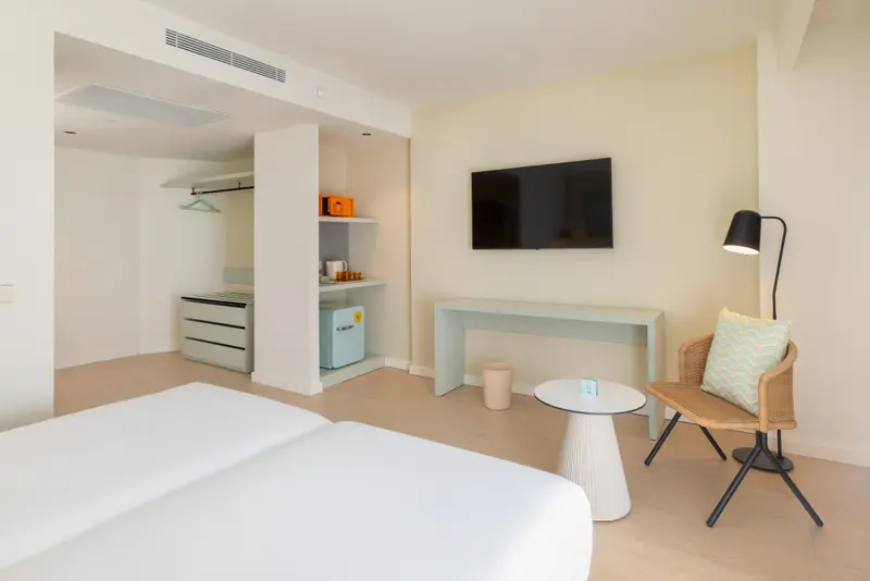 Une chambre lumineuse avec un lit, un espace bureau et un coin salon.