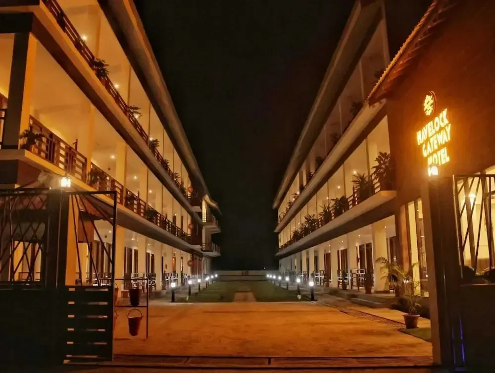 Allée illuminée mène à un bâtiment à deux étages avec des balcons.