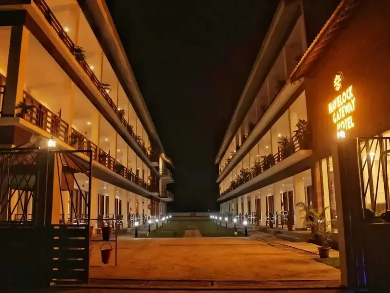 Allée illuminée mène à un bâtiment à deux étages avec des balcons.