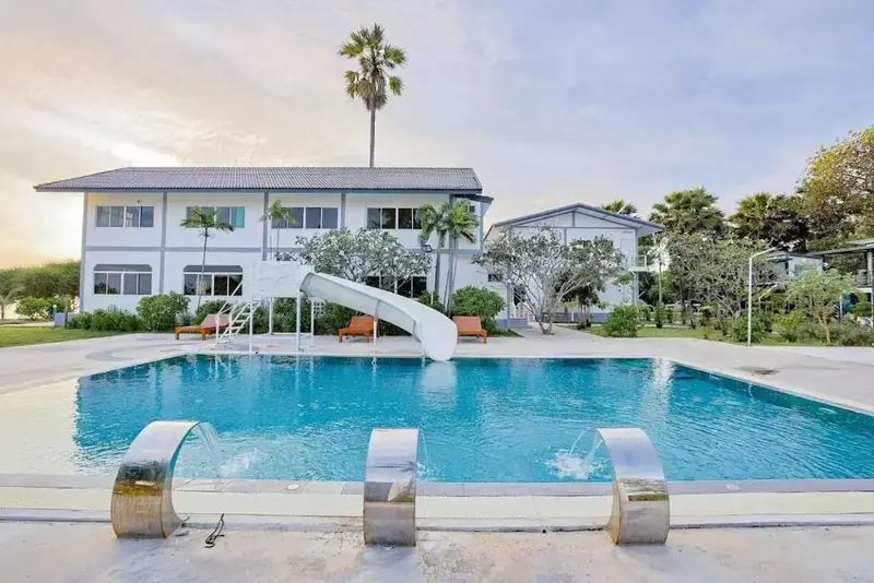 Une piscine rectangulaire avec un toboggan et un bâtiment en arrière-plan.