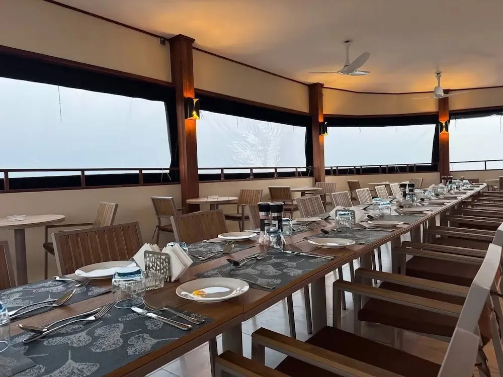 Une longue table est dressée pour un repas dans une salle à manger lumineuse.