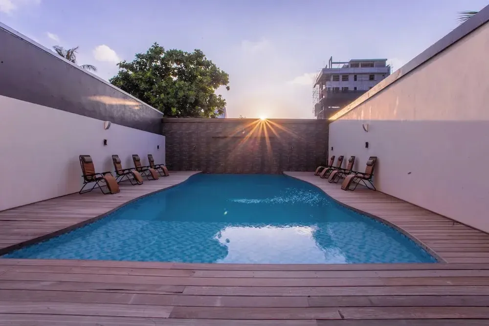 Une piscine rectangulaire entourée d'une terrasse en bois et de chaises longues.
