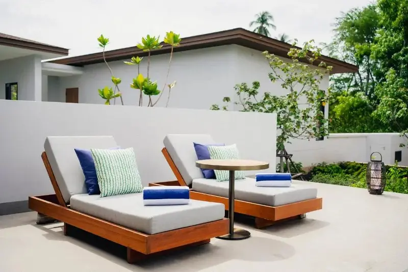 Deux chaises longues avec coussins et serviettes sur une terrasse ensoleillée.