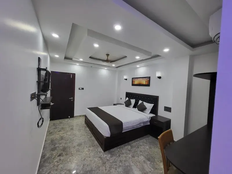 Une chambre lumineuse avec un grand lit et une télévision murale.