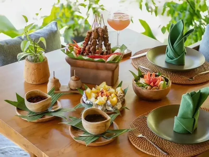 Une table en bois est dressée avec des plats variés et des couverts.