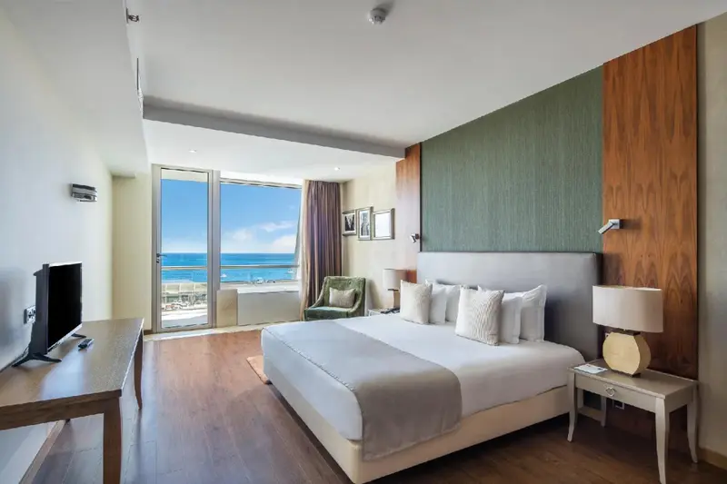 Une chambre lumineuse avec un grand lit donnant sur la mer.