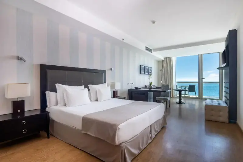Une chambre lumineuse avec un grand lit et une vue sur la mer.