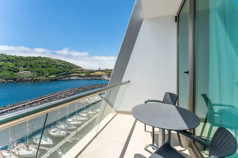 Une terrasse avec vue sur un port de plaisance et une colline verdoyante.