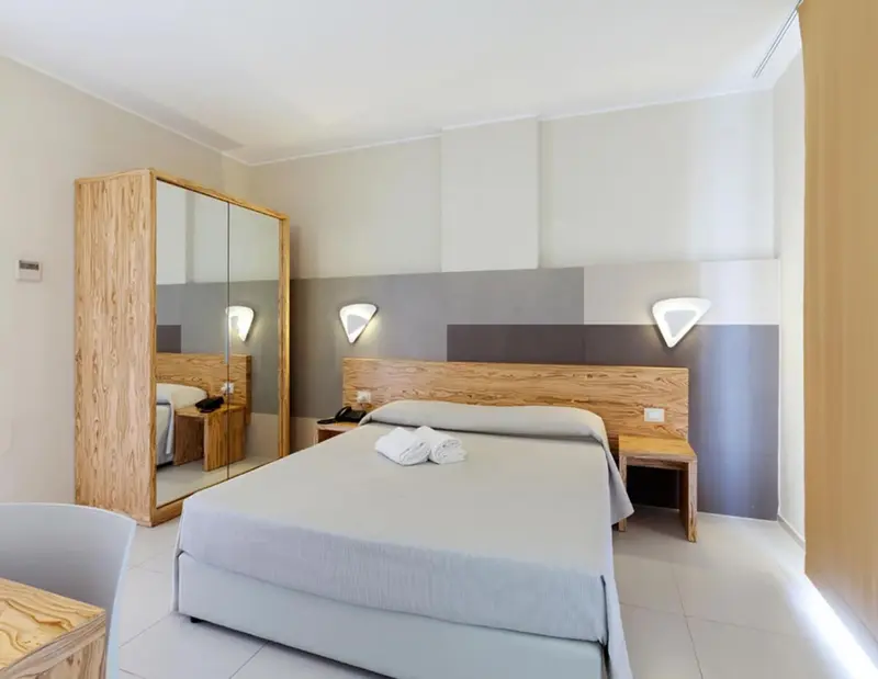 Une chambre lumineuse avec un lit double et un meuble de rangement en bois.