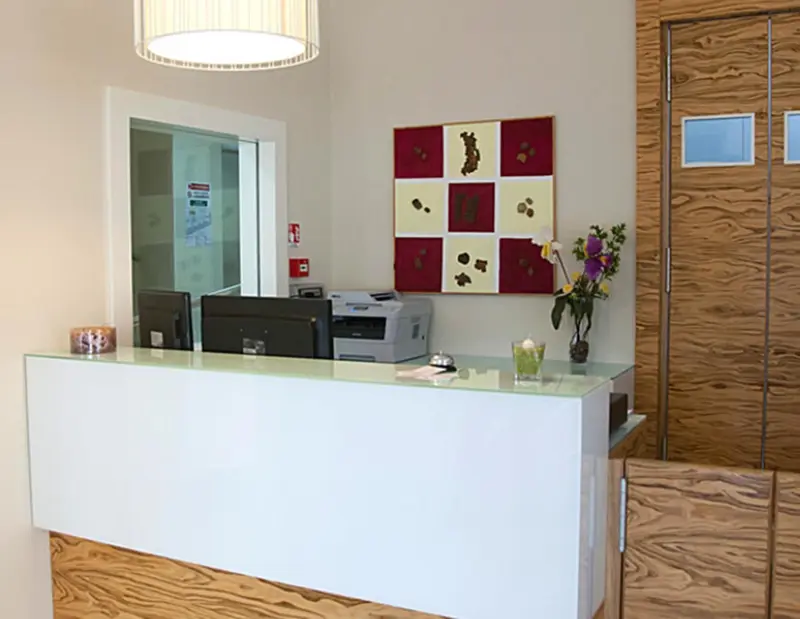 Un comptoir d'accueil moderne avec un ordinateur et une décoration murale.
