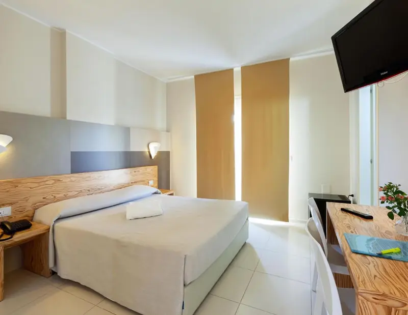 Une chambre lumineuse avec un grand lit et un bureau en bois.