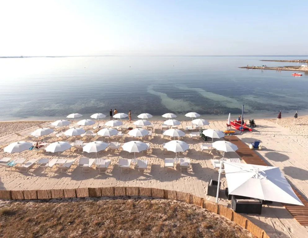 Plage de sable fin avec parasols et transats en bord de mer.