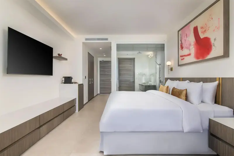 Une chambre lumineuse avec un grand lit et une télévision murale.