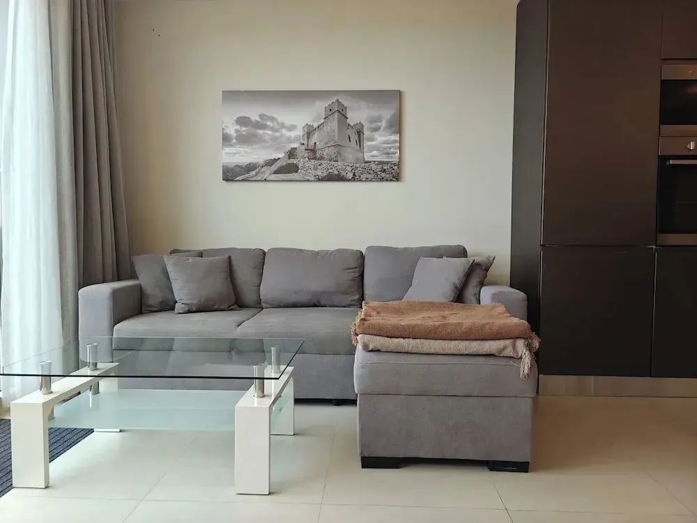 Un salon moderne avec un canapé d'angle et une table basse en verre.