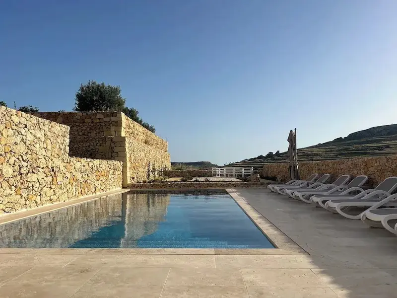 Une piscine rectangulaire bordée d'une terrasse ensoleillée avec des transats.