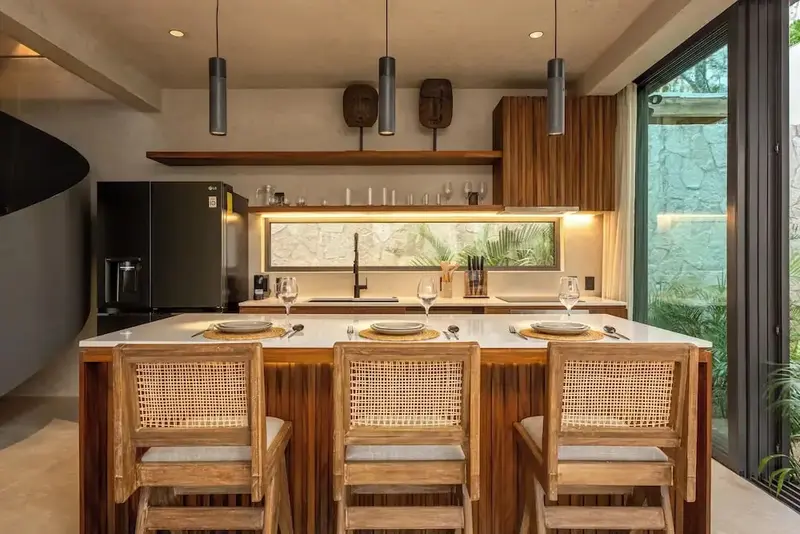 Une cuisine moderne avec un îlot central et des tabourets en bois.