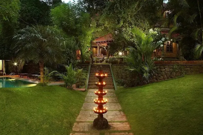 Un chemin illuminé mène à un bâtiment entouré de végétation luxuriante.